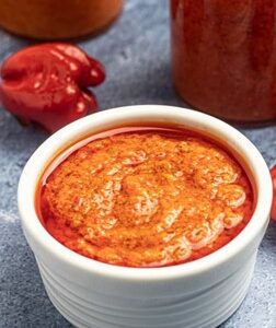 Pepper sauce in a bowl beside Beignet
